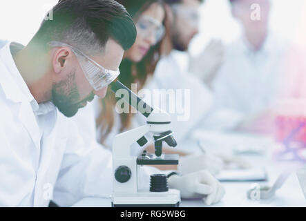 Scienziato cercando in una seduta di microscopio in laboratorio. Foto Stock