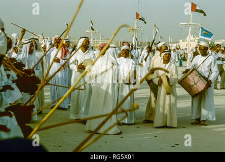 Dubai. Arab festeggiamenti nuziali con gli uomini nel tradizionale abito araba generalmente si diverte, canto, danza, sfilano in Emirato di Dubai in 1986 Foto Stock