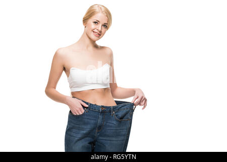 Bella felice slim donna in jeans oversize sorridente in telecamera isolato su bianco Foto Stock