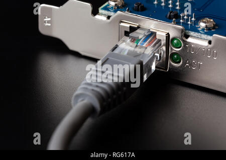 Scheda di rete per computer con cavo collegato su sfondo nero close up Foto Stock