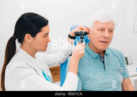 Esame medico paziente anziano orecchio , utilizzando un otoscopio, medici in ufficio. Senior man getting medical orecchio esame presso una clinica. Foto Stock