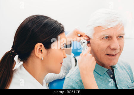 Esame medico paziente anziano orecchio , utilizzando un otoscopio, medici in ufficio. Senior man getting medical orecchio esame presso una clinica. Foto Stock