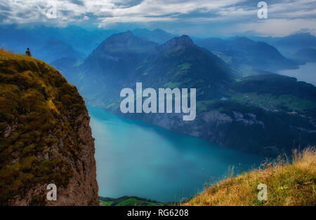 Uomo in piedi sul monte Fronalpstock guardando giù al lago, Svitto, Svizzera Foto Stock