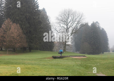 Uomo che cammina attraverso un ponte su un campo da golf in inverno, Germania Foto Stock