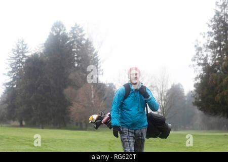 Un uomo su un campo da golf che porta una sacca da golf in inverno, Germania Foto Stock