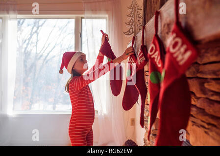 Ragazza appendere le calze di Natale su un caminetto Foto Stock