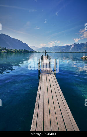 Donna sta posando al molo sul Lago di Ginevra, vicino al Castello di Chateau de Chillon vicino a Montreux, Svizzera Foto Stock