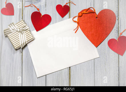 White Busta lettera e presente su bianco tavolo in legno, il giorno di San Valentino concetto Foto Stock