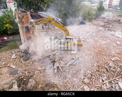 Grande escavatore decostruzione dei edificio. costruzione pesante macchina circondata con le rovine Foto Stock