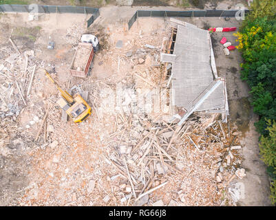 Escavatore e autocarro con cassone ribaltabile clearing out site dopo la demolizione del vecchio edificio abbandonato Foto Stock