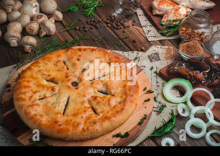 In casa torta a base di carne con pollo e funghi su un sfondo di legno con ingredienti. La cucina tradizionale concetto con colori caldi Foto Stock