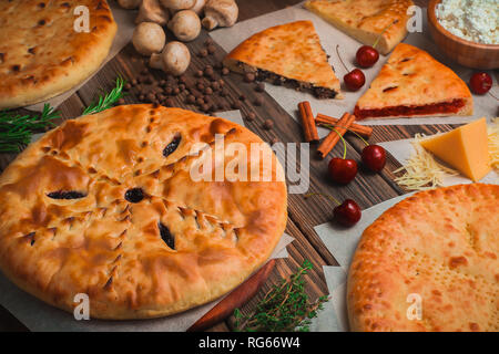 Un assortimento di torte fatte in casa n un sfondo di legno con ingredienti. La cucina tradizionale concetto con colori caldi e uno spazio di copia Foto Stock