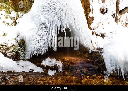 Voglia di ghiaccioli e gocce d'acqua, pietre colorate nel torrente, inverno stato di natura Foto Stock