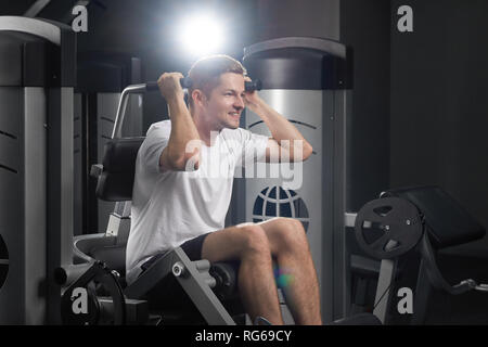 Closeup idoor ritratto di ypung attraente montare concentrata sirious sportivo in palestra. Forte sorridente fiducioso atleta facendo esercizi spesial utilizzando attrezzature sportive in palestra. Concetto di stile di vita. Foto Stock