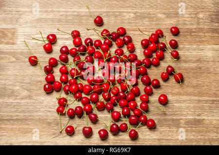 Fresche ciliege mature con gocce di acqua su un tavolo di legno. Vista superiore o laici piatta Foto Stock