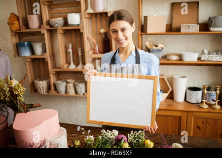 Sorridente fioraio Holding firmano Foto Stock