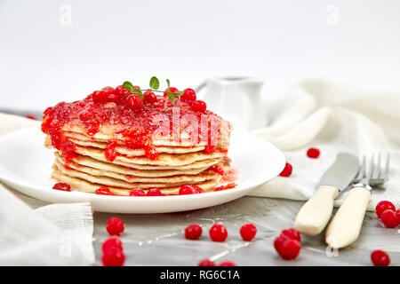 American pancake con la marmellata - berry, pallon di maggio, mirtillo rosso su sfondo grigio. Pancake fatti in casa con salsa di frutti di bosco e le foglie di menta. Sana colazione con prodotti freschi h Foto Stock