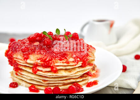American pancake con la marmellata - berry, pallon di maggio, mirtillo rosso su sfondo grigio. Pancake fatti in casa con salsa di frutti di bosco e le foglie di menta. Sana colazione con prodotti freschi h Foto Stock
