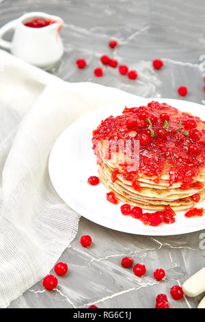 American pancake con la marmellata - berry, pallon di maggio, mirtillo rosso su sfondo grigio. Pancake fatti in casa con salsa di frutti di bosco e le foglie di menta. Sana colazione con prodotti freschi h Foto Stock