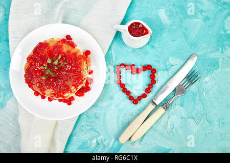 Cuore dal Berry. American pancake con la marmellata - berry, pallon di maggio, mirtillo rosso su sfondo blu. Pancake fatti in casa con salsa di frutti di bosco e le foglie di menta. Brea sani Foto Stock