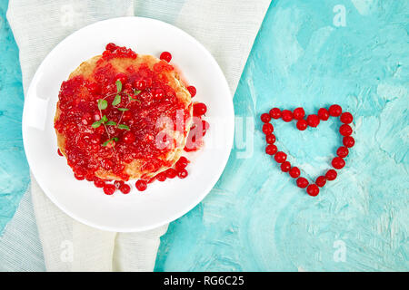 Cuore dal Berry. American pancake con la marmellata - berry, pallon di maggio, mirtillo rosso su sfondo blu. Pancake fatti in casa con salsa di frutti di bosco e le foglie di menta. Brea sani Foto Stock