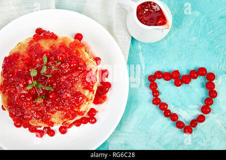 Cuore dal Berry. American pancake con la marmellata - berry, pallon di maggio, mirtillo rosso su sfondo blu. Pancake fatti in casa con salsa di frutti di bosco e le foglie di menta. Brea sani Foto Stock