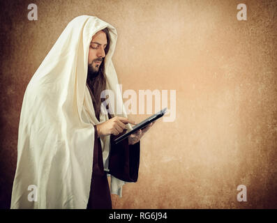 Gesù Cristo si legge la Sacra Bibbia con il tablet Foto Stock