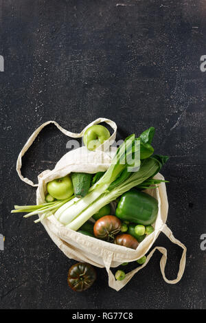 Verde assortimento di cibo con tessuto Eco borsa su sfondo scuro copia vista dall'alto dello spazio laico piana. Concetto di consumo consapevole Foto Stock