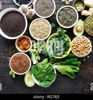 Dieta bilanciata cibo materie semi, cereali, fagioli, superfoods e verdura verde scuro sul tavolo di legno vista dall'alto. Vegetariano o cucina dietetica Foto Stock