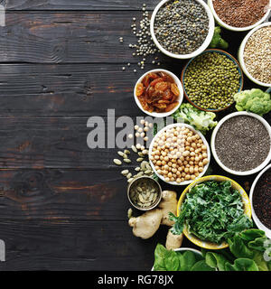 Dieta bilanciata cibo materie semi, cereali, fagioli, superfoods e verdura verde scuro sul tavolo di legno vista dall'alto. Vegetariano o cucina dietetica Foto Stock