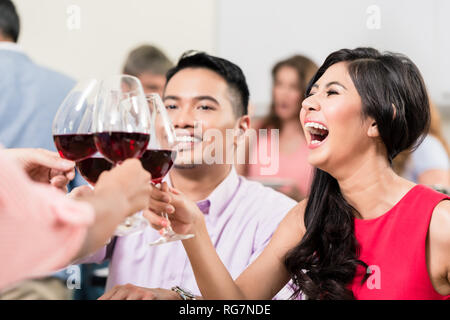 Donna wineglasses tostatura con gli amici Foto Stock
