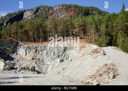 Escavatore a piccola cava in Norvegia, in Scandinavia, costruzione di data mining aggregato e riprap Foto Stock