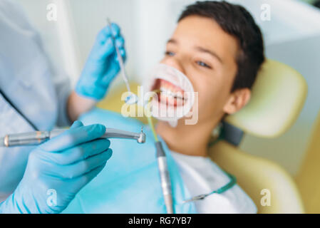 Guarnizione di tenuta del processo di installazione, odontoiatria pediatrica, bambini stomatologia. Dentista femmina funziona con little boy in clinica dentale Foto Stock