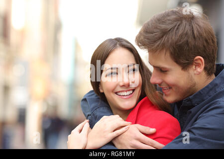 Felice ragazza con perfetta denti essendo abbracciato con il suo fidanzato in strada Foto Stock