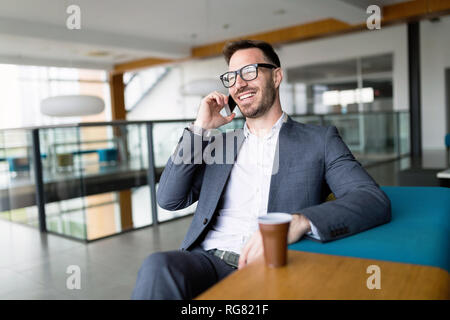 Pensieroso giovane imprenditore nel cafe usando il telefono Foto Stock