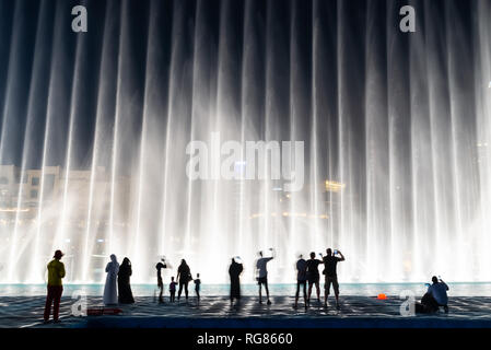 Sagome di persone godendo la fontana show di Dubai di notte, Emirati Arabi Uniti Foto Stock