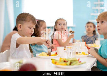 Un gruppo di bambini sani godendo il pranzo in asilo nido Foto Stock