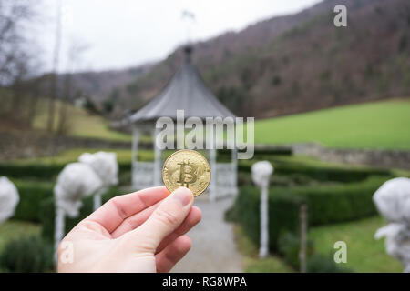 Bitcoin moneta in oro, mano tenere bitcoin nel parco e sfondo naturale Foto Stock