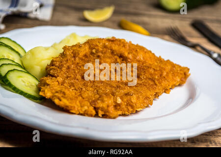 Chicken fried schnitzel con purè di patate e limone sul tavolo di legno Foto Stock