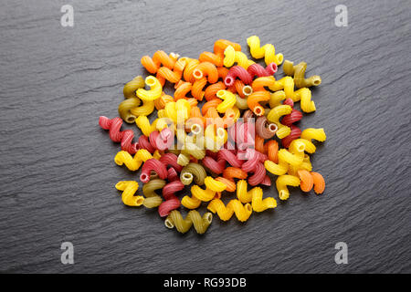 Spirale multicolore pasta sparsi su un nero ardesia sfondo. spazio per il testo Foto Stock