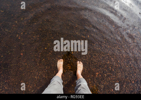 I piedi di un uomo in acqua di un lago Foto Stock