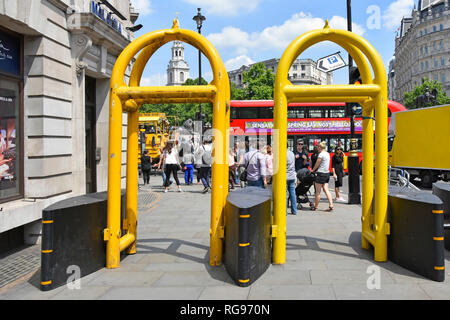 Acciaio giallo archi accanto a girevoli anti terrore delle barriere di sicurezza sul marciapiede di aiutare con controllo della folla & anti terrorismo del veicolo in Londra England Regno Unito Foto Stock
