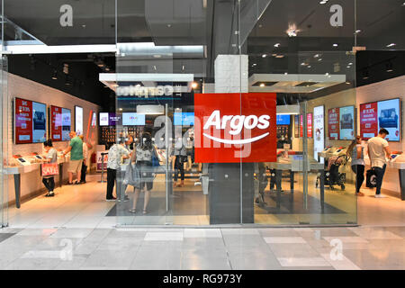 Gli amanti dello shopping dietro il palazzo di vetro negozio finestra anteriore in corrispondenza di Argos catalogo carrello negozio in Westfield Mall in città di Stratford Newham Est Londra Inghilterra REGNO UNITO Foto Stock