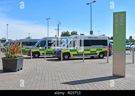 Fila di G4S di somministrazione al paziente ambulanza sanitaria parcheggiata fuori l'ingresso principale segno di NHS Queens Hospital Romford Havering Est Londra Inghilterra REGNO UNITO Foto Stock