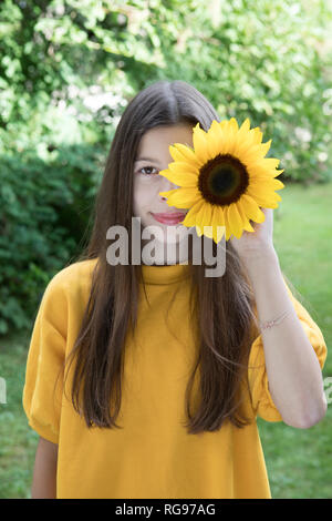 Ritratto di ragazza sorridente con il girasole in giardino Foto Stock