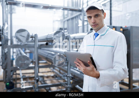 Il Tecnologo con una compressa nelle sue mani presso il caseificio Foto Stock