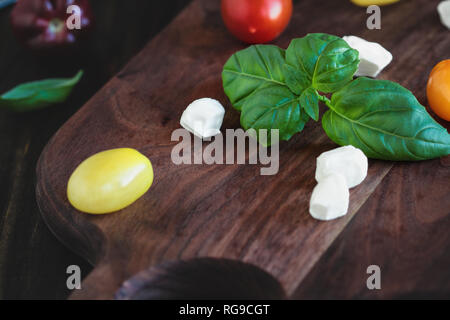 Fresco dal giardino di basilico e cimelio di pomodori con mozzarella per insalata caprese, cibo italiano e una sana dieta vegetariana concetto, oltre a r Foto Stock