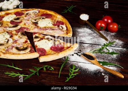 Italian fast food. Una deliziosa pizza calda tagliate a fette e servite sul piatto di legno con ingredienti, vista ravvicinata. Menu foto. Foto Stock