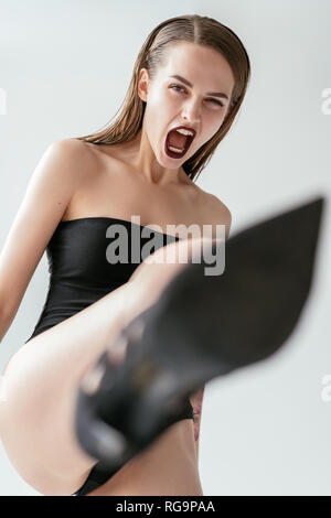 Aggressivo grida donna calci gamba in alto le scarpe per telecamera. Il concetto di stress Foto Stock