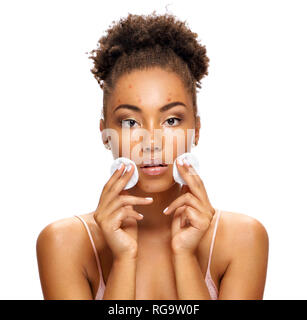 Ragazza giovane con il problema della pelle azienda tamponi di cotone vicino al viso. Foto di African American Girl isolati su sfondo bianco. Cura della Pelle concept Foto Stock